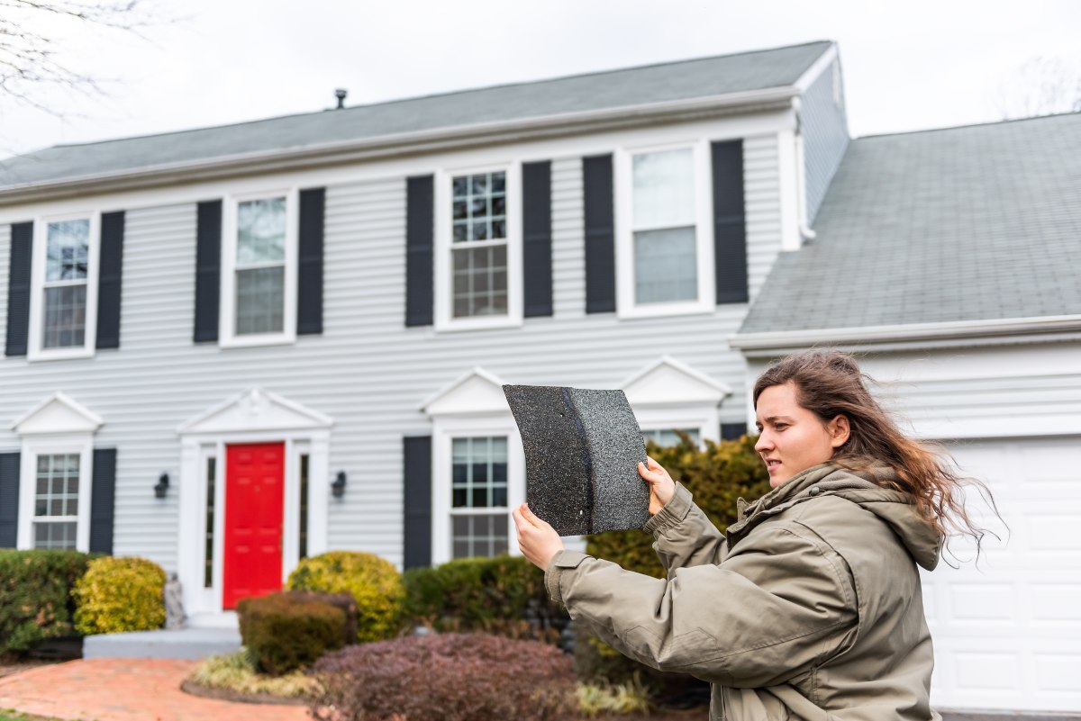 Woman comparing roof shingles on a windy day in Ohio