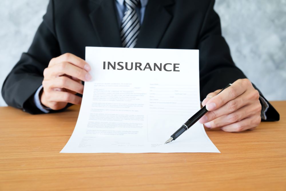 Man holding a paper with the word insurance on it.