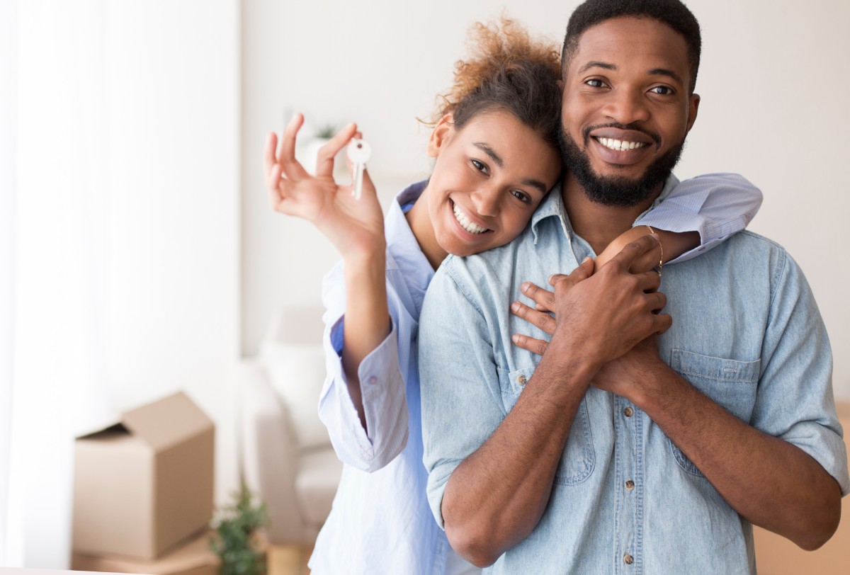 A young couple proudly hold the key to their new home that they've recently moved into.